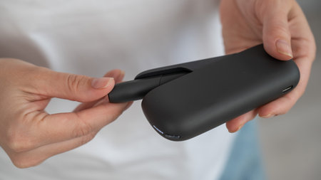 A woman takes a tobacco heating system out of a charger. Electronic cigaretteの写真素材