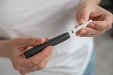 A woman inserts a cigarette stick into a tobacco heating system. Electronic cigarette