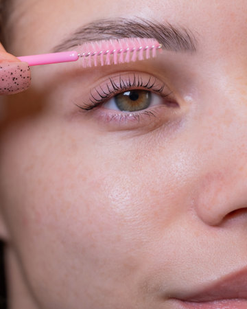 Caucasian woman brushing her eyelashes after laminationの写真素材