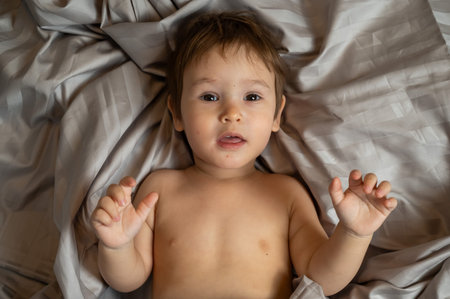 Top view of cute caucasian toddler lying in bed