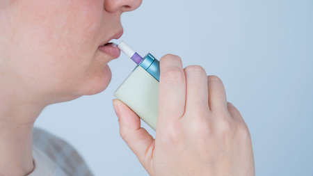 Caucasian woman using an inhaler.