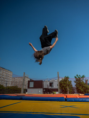 A girl jumps on an outdoor trampolineの写真素材