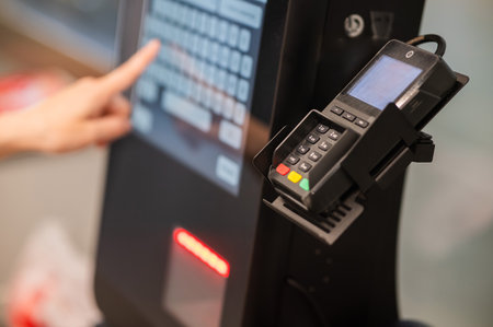 A woman uses a self-checkout machineの写真素材