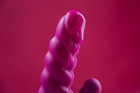 Lube pouring on pink dildo on pink background