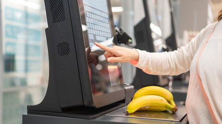 Faceless woman using self-checkout technology at grocery store