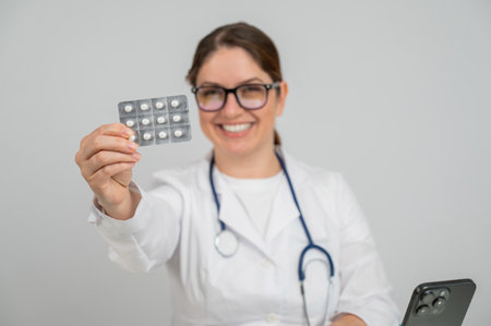 A female doctor sits at a table and recommends pillsの写真素材
