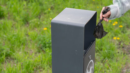 Responsible Dog Owner Disposing of Waste in Park Binの写真素材