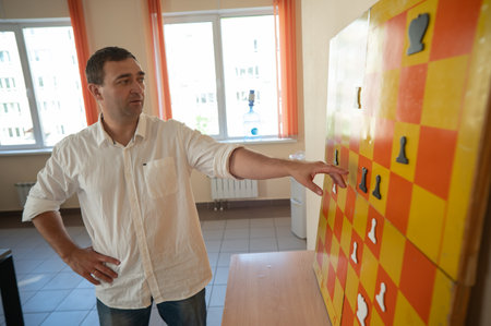 Caucasian man standing at wall mounted magnetic chessboard demonstrationの写真素材