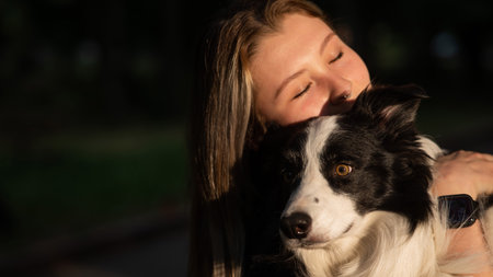 Young Caucasian woman hugging her border collie dog while walking in the parkの写真素材
