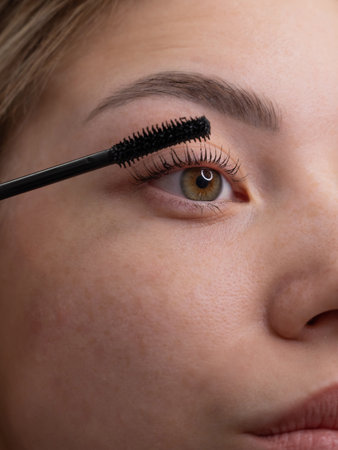 Close-up of a young woman intently applying mascara to her eyelashesの写真素材