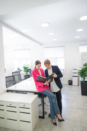 Colleagues look at a folder with documents and discuss work issues