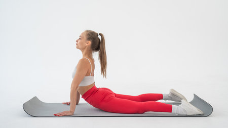 Young woman doing cobra exercises on white backgroundの写真素材