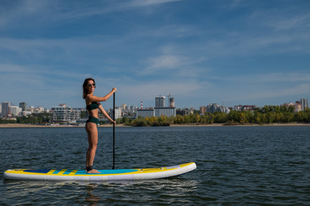 Caucasian woman riding a SUP board on the lake. Summer sportの写真素材