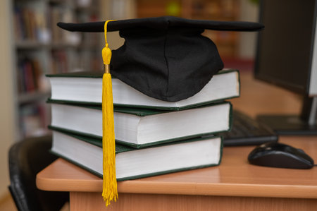 Graduation cap on a stack of books in the libraryの写真素材