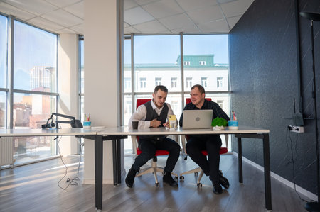 Two Caucasian men sitting at a table and discussing workの写真素材