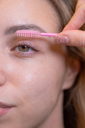 Caucasian woman brushing her eyelashes after laminationの写真素材