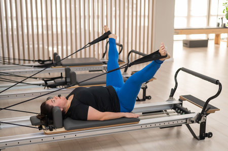 Overweight caucasian woman doing pilates exercises on a reformerの写真素材