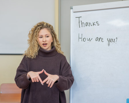 Caucasian female teacher communicates in Russian sign language with studentsの写真素材