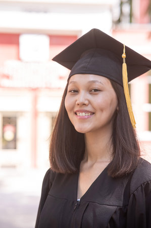 Happy young asian woman in graduation gown