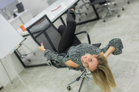 Caucasian woman having fun and lying on office chairの写真素材