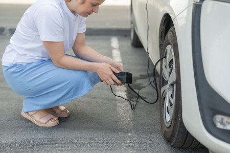 A woman pumps up a tire on a carの写真素材