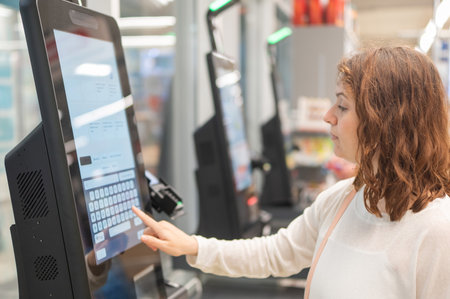 Caucasian woman using self-checkout technology at grocery storeの写真素材