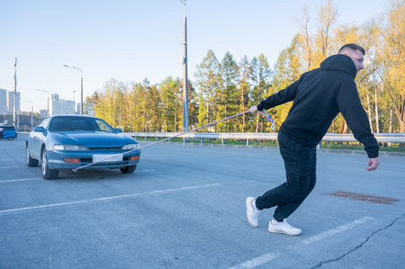 Caucasian man pulling a car with a ropeの写真素材