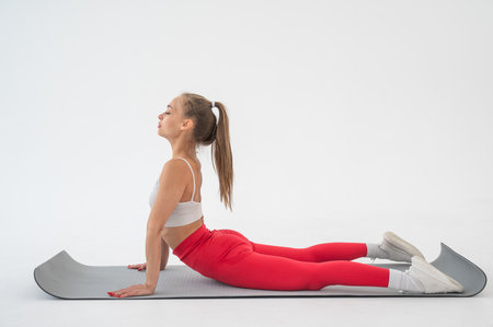 Young woman doing cobra exercises on white backgroundの写真素材