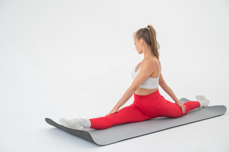 Young woman doing splits exercises on white backgroundの写真素材