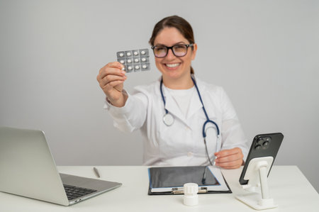 A female doctor sits at a table and recommends pillsの写真素材