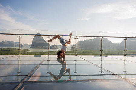 Caucasian woman doing forearm stand on glass bridge among mountainsの写真素材