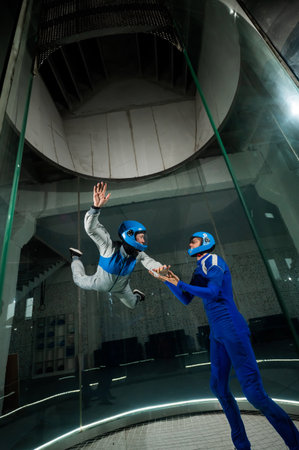 A male instructor teaches a woman how to fly in a wind tunnel. Free fall simulatorの写真素材