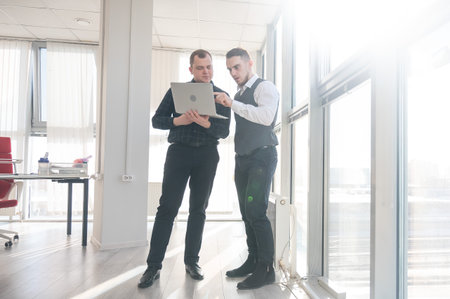 Two Caucasian men looking at a laptop and discussing workの写真素材