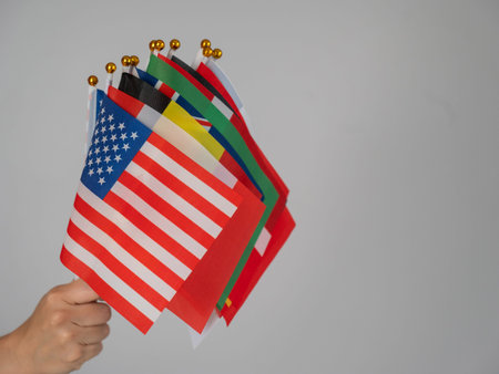 A womans hand holding a bunch of small flags of different countries