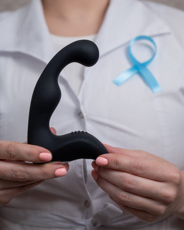 Female doctor holding prostate massager and blue ribbon. Symbol of fight against prostate cancer