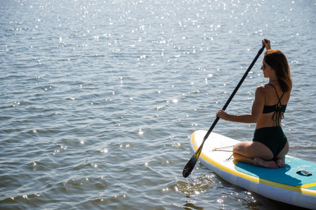 Beautiful caucasian woman is swimming on a SUP board