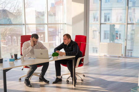 Two Caucasian men solve problems at workの写真素材