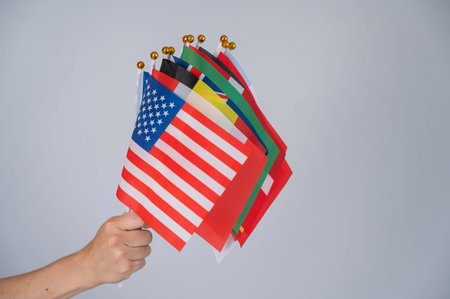 A womans hand holding a bunch of small flags of different countries
