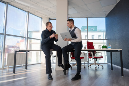 Two Caucasian men discussing work in an office.の写真素材