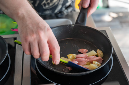 The chef fries potatoes and sausagesの写真素材