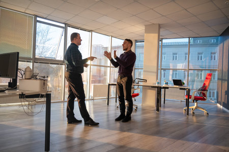 Two Caucasian men talking at work in the office