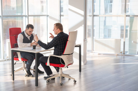 Two Caucasian men using smartphones while sitting at a desk