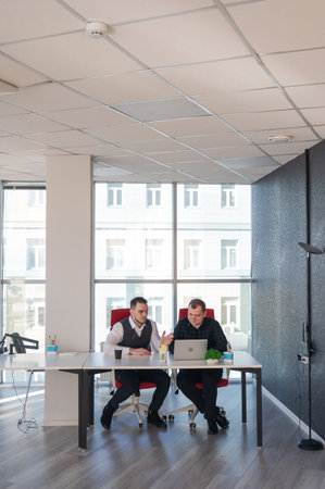 Two Caucasian men sitting at a table and discussing workの写真素材
