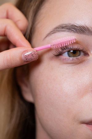 Caucasian woman brushing her eyelashes after lamination
