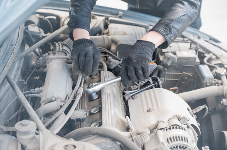 A man changes spark plugs in his car