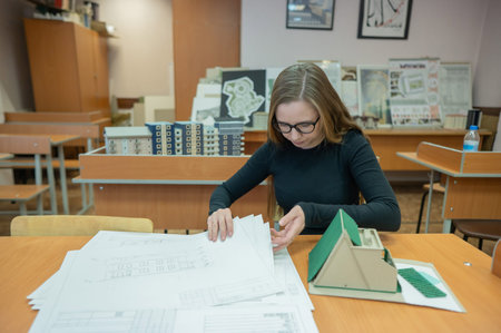 Caucasian young woman making a model of a building. Student of the construction university