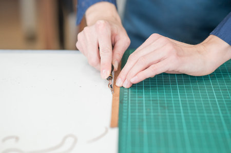 Leatherworker measuring and cutting leather in workshop