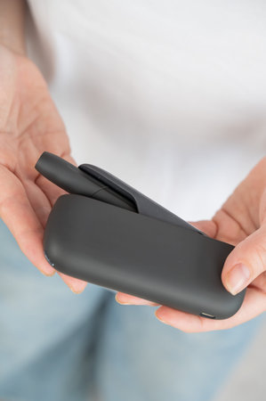 A woman takes a tobacco heating system out of a charger. Electronic cigaretteの写真素材