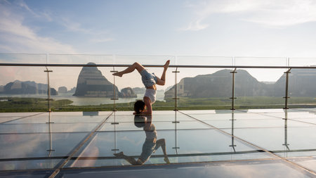 Caucasian woman doing forearm stand on glass bridge among mountains