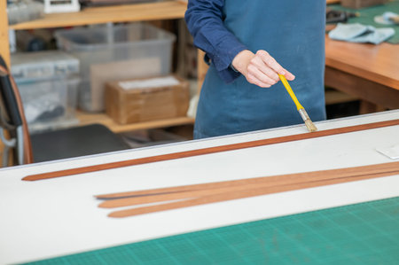 A craftsman uses a brush to cover leather parts